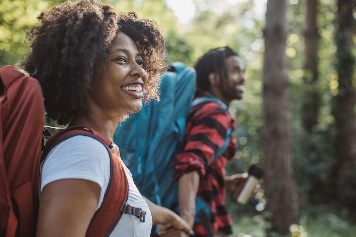 A couple holding hands and smiling on a hike through the woods.